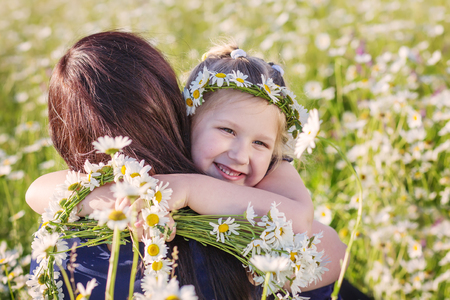 Mother with cute little child girl in the chamomile field in springの写真素材