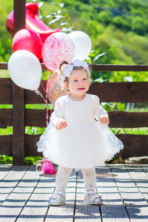 Little baby in white dress with balloons outdoorsの写真素材