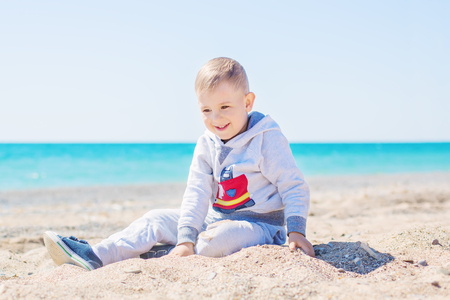 Cute little boy is playing in the sand on the beachの写真素材