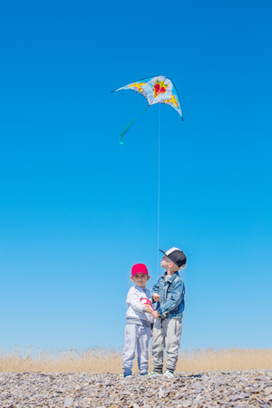 Two happy children with a kite on the coastの写真素材