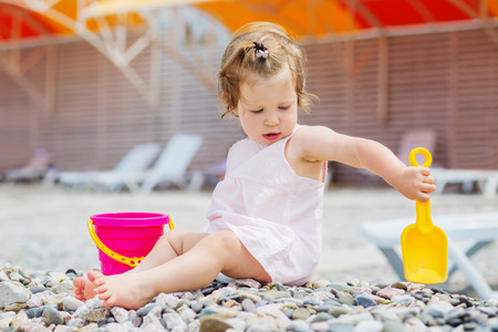 a baby girl is playing with her toys on the beachの写真素材
