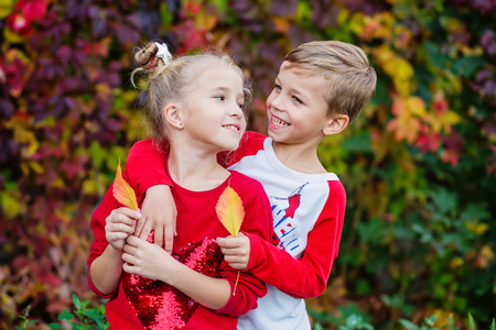 Happy children playing in beautiful autumn park on warm sunny fall day. Kids play with  leaves.の写真素材