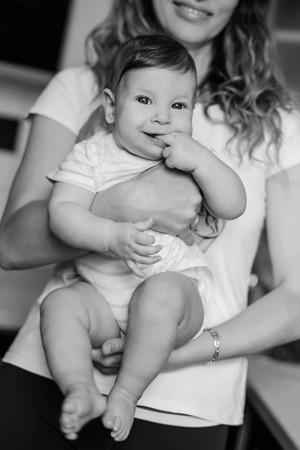 happy mother holds a six-month-old baby in her arms in the kitchen ( black and white )の写真素材