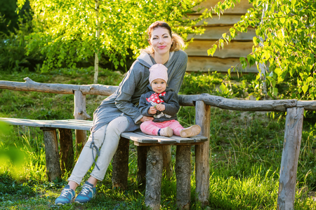 Mother and daughter in the park in spring time sitting on the benchの写真素材