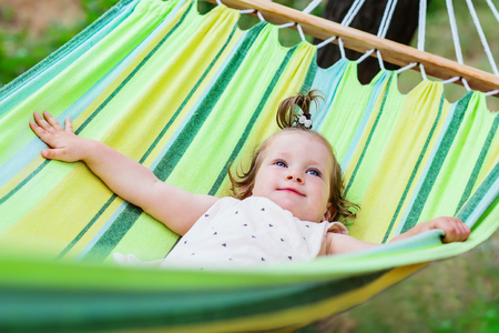 happy baby  is relaxing in a hammock during summer in the gardenの写真素材