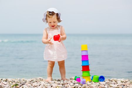 Cute toddler girl playing with colorful toys on the beachの写真素材