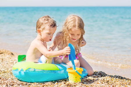 small children are playing on the beach with a bucket and rubber ringの写真素材