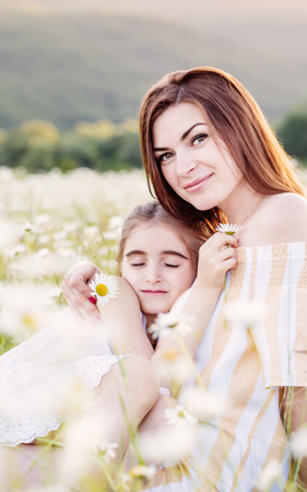 Mother and daughter in  field of daisies. Beautiful family in nature.の写真素材