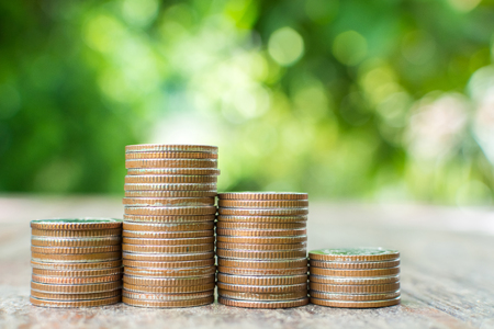 Coin stack on wood table with background blurred green leaf, Save money and investment conceptの写真素材