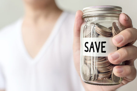Hand holding money coin in jar with word save on tag, Concept save money business investmentの写真素材