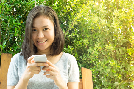 Asian woman hand using mobile phone in garden with copy spaceの写真素材