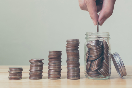 Hand of male or female putting coins in jar with money stack step growing growth saving money, Concept finance business investmentの写真素材