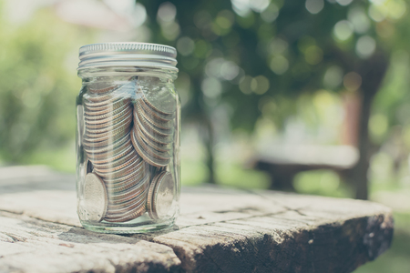 Coin in bottle glass on wood table with blurred green garden backgroundの写真素材
