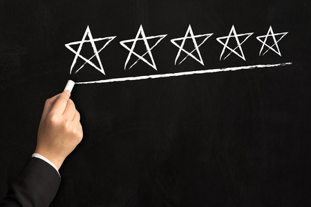 Hand of businessman writing five star on black board, Business increase rating of company conceptの写真素材