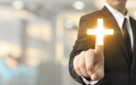 Businessman hand touching plus sign with blurred background, Business offer positive, benefit and development conceptの写真素材