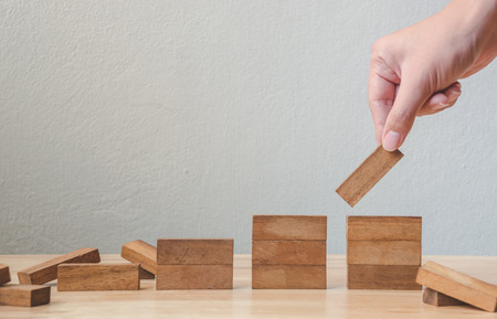 Hand arranging wood block stacking as step stair. Business concept for growth success processの写真素材
