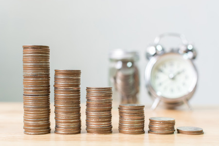 Coin stack step up increase save money with blurred clock and jar background, Finance and investment conceptの写真素材