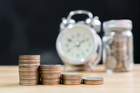 Coin stack step up increase save money with blurred clock and jar background, Finance and investment conceptの写真素材