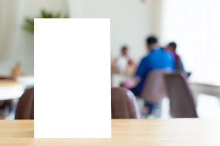 Mock up blank template menu frame on wood table in restaurant with blurred background, Clipping path includedの写真素材