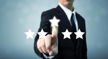 Businessman pointing five star symbol to increase rating of companyの写真素材
