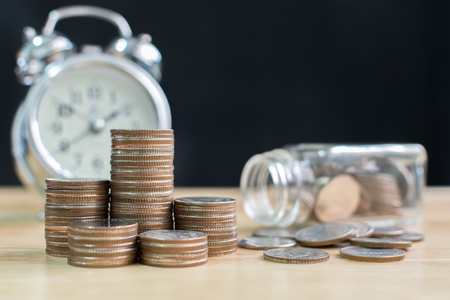 Coin stack with blurred clock and jar background, Finance and investment save money conceptの写真素材