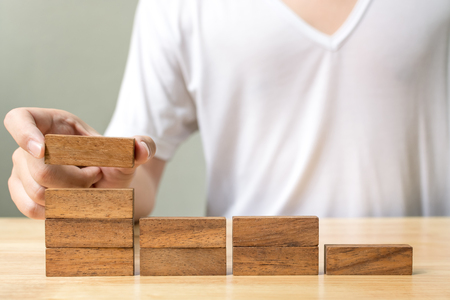 Hand of male arranging wood block stacking as step stair. Business concept for growth success processの写真素材