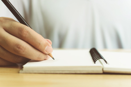Hand of man with pencil writing on notebookの写真素材