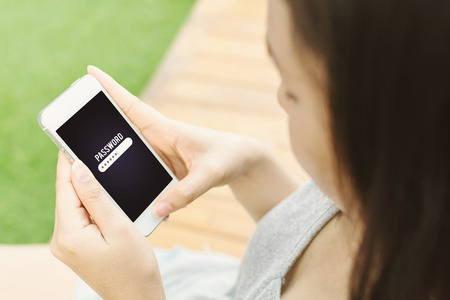 Woman hand holding mobile phone and entering password on screen, Smartphone security data protection conceptの写真素材