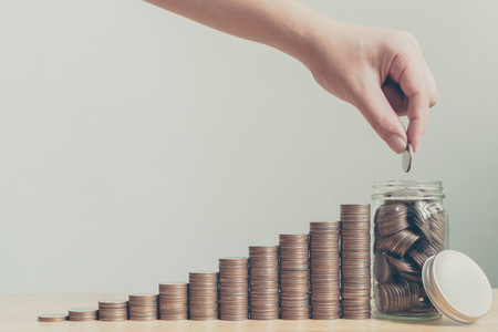 Hand of male or female putting coins in jar with money stack step growing growth saving money, Concept finance business investment, Copy space for your textの写真素材