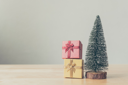 Christmas tree and gift box red, yellow color on wood table with white wall background, Christmas holiday celebration and boxing day concept, Copy spaceの写真素材