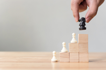 Business leadership concept with chess on top wood block ladder staircase. Team leading career for teamworkの写真素材