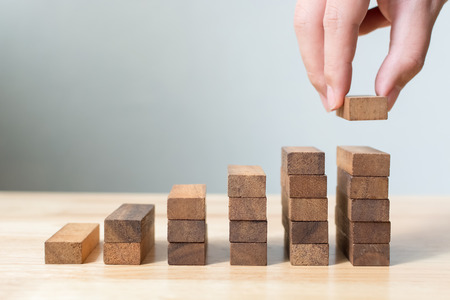 Hand arranging wood block stacking as step stair. Ladder career path concept for business growth success process, Copy spaceの写真素材