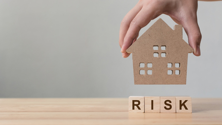 Property investment and house mortgage financial. Risk management concept. Hand putting wooden home on wood block with wordの写真素材