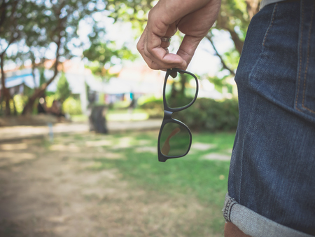 Hipster men's hand holds glasses while traveling in natural parkの写真素材
