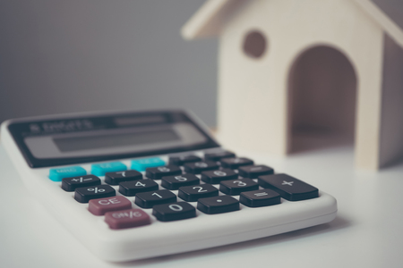 Calculator with wooden house on white table. Property investment and house mortgage financial conceptの写真素材