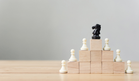 Business leadership concept with chess on top wood block ladder staircase. Team leading career for teamworkの写真素材