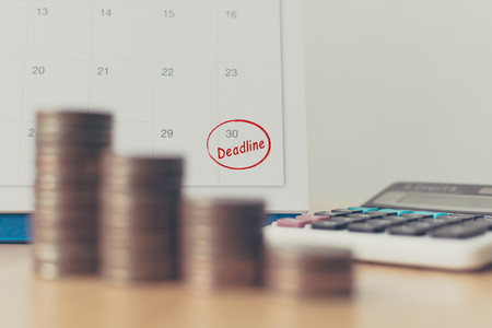 Tax payment season and finance debt collection deadline concept. Money coins stack, calendar and calculatorの写真素材