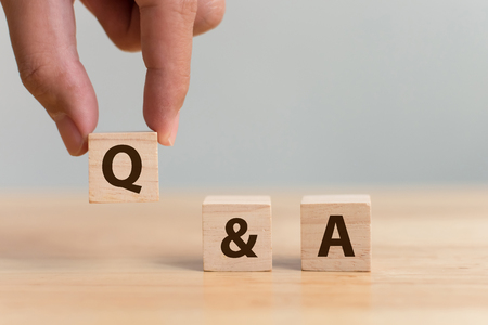 Questions and answers concept. Hand putting wood block cube with alphabet Q&A on wooden tableの写真素材