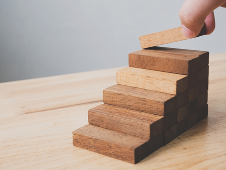 Hand arranging wood block stacking as step stair. Ladder career path concept for business growth success process, Copy spaceの写真素材