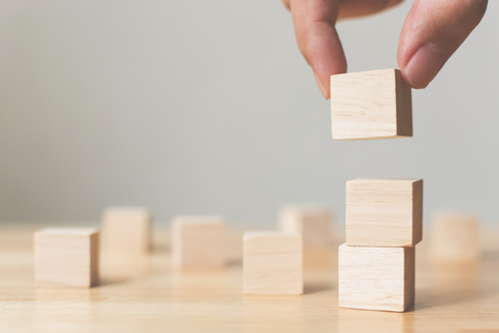 Hand arranging wood block stacking on top with wooden table. Business concept for growth success process. Copy spaceの写真素材