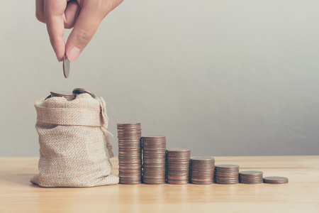 Hand of male or female putting coins in money bag with coin stack step growing growth saving money, Concept finance business investmentの写真素材