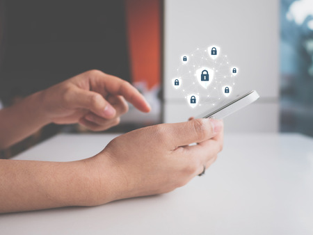 Data protection and security important information in your mobile phone, Woman hand using smartphone and icon key on shieldの写真素材