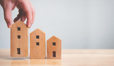 Property investment real estate and house mortgage financial concept. Hand holding wooden home on tableの写真素材