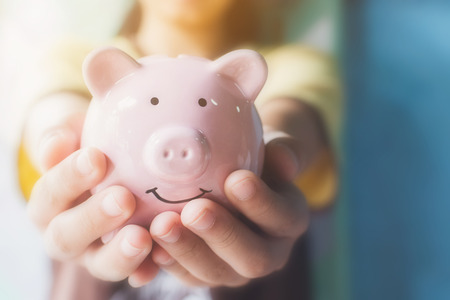 Female hand holding piggy bank. Save money and financial investmentの写真素材