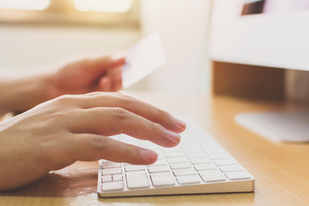 Hand holding credit card and using computer desktop. Online shopping payment and e-commerce conceptの写真素材