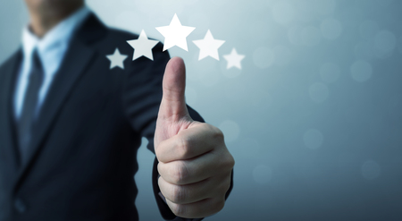Businessman showing hand sign thumb up and five star symbol to increase rating of company, The excellence of the business or service conceptの写真素材