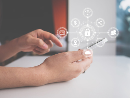 Data protection and security important information in your mobile phone, Woman hand using smartphone and icon key on shieldの写真素材