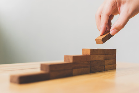 Hand arranging wood block stacking as step stair. Ladder career path concept for business growth success processの写真素材