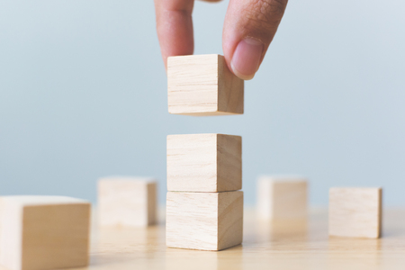 Hand arranging wood block stacking on top with wooden table. Business concept for growth success processの写真素材
