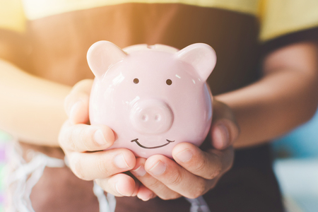 Female hand holding piggy bank. Save money and financial investmentの写真素材